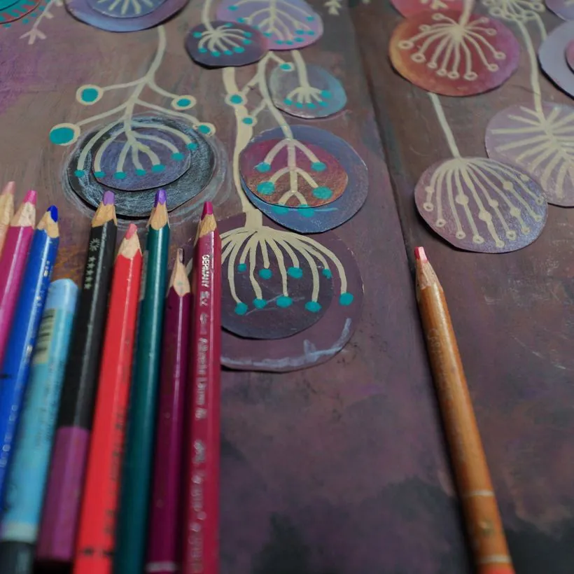 Coloured pencils laid beside hand-painted paper circles with gold linework